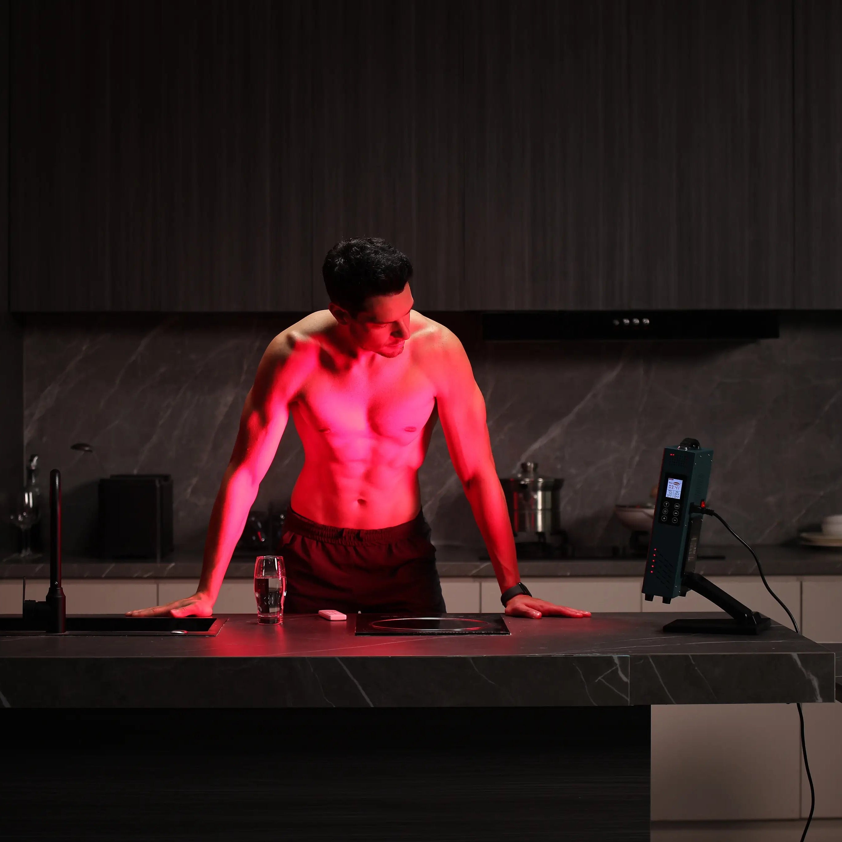 Home red light therapy session with YouLumi desktop panel on counter, targeting the torso