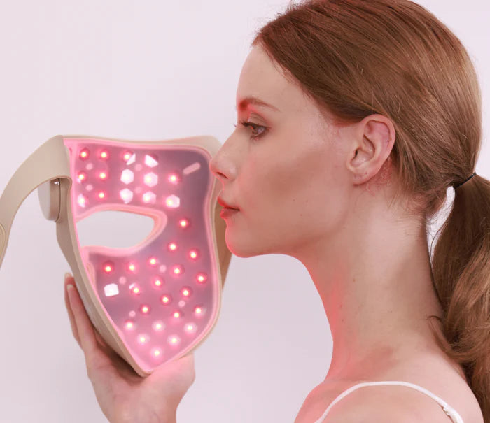 Woman using Youlumi Y02 red light therapy mask with active red LEDs for facial skincare