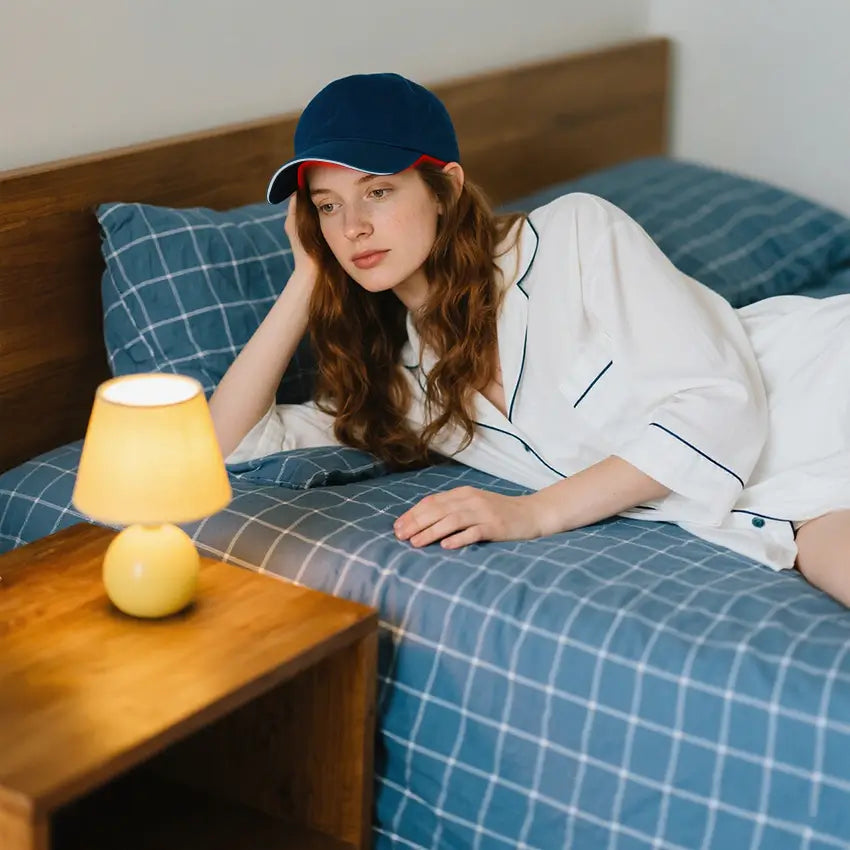 Person wearing a red light therapy cap while lying in bed