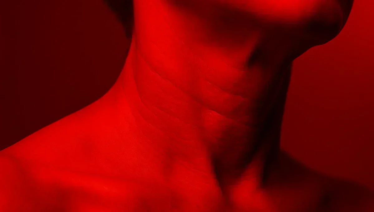 Close-up of a person's neck illuminated in red light therapy, showing the contours and skin texture under red light treatment