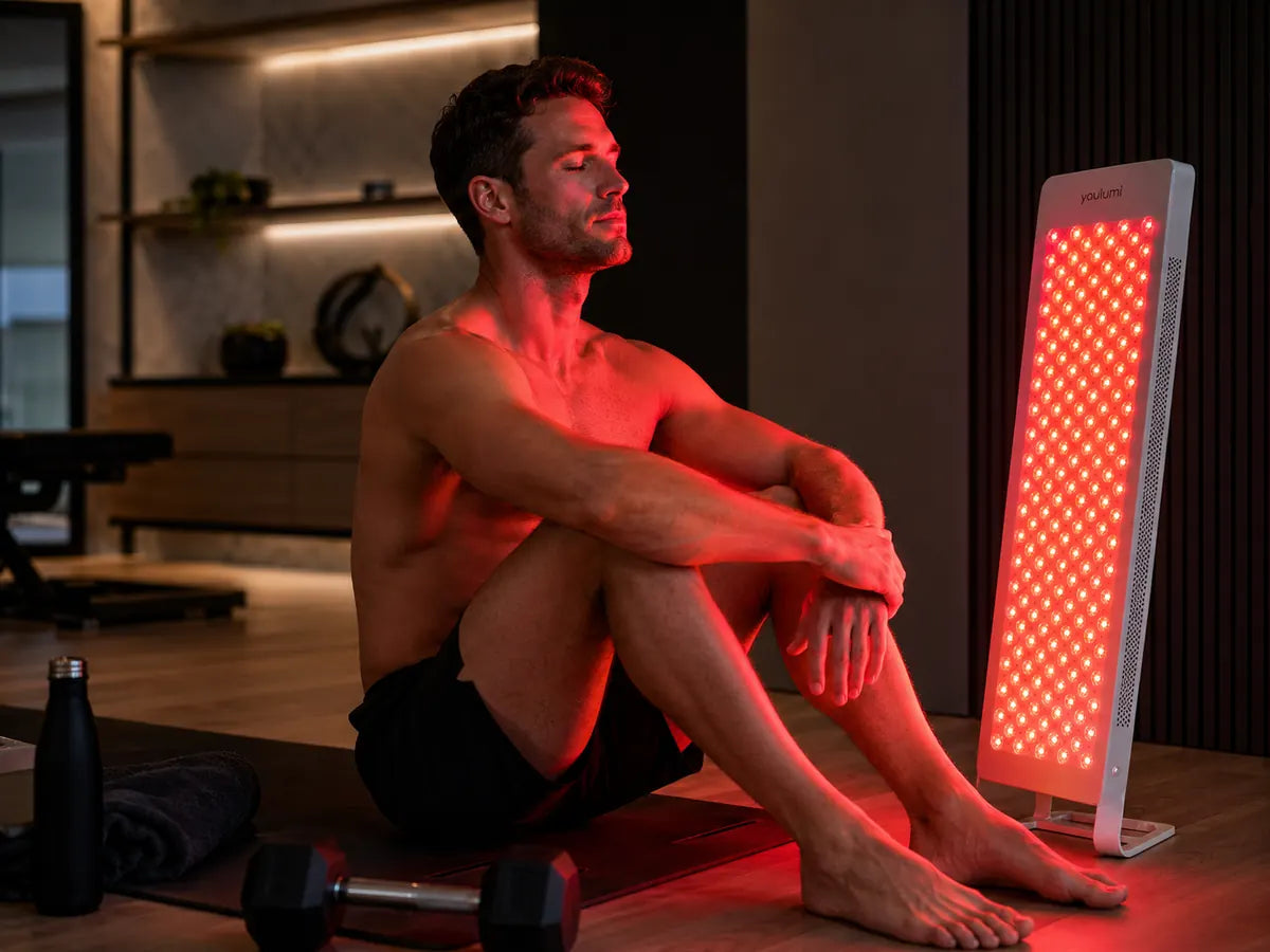 A man using a red light therapy panel at home after a workout session