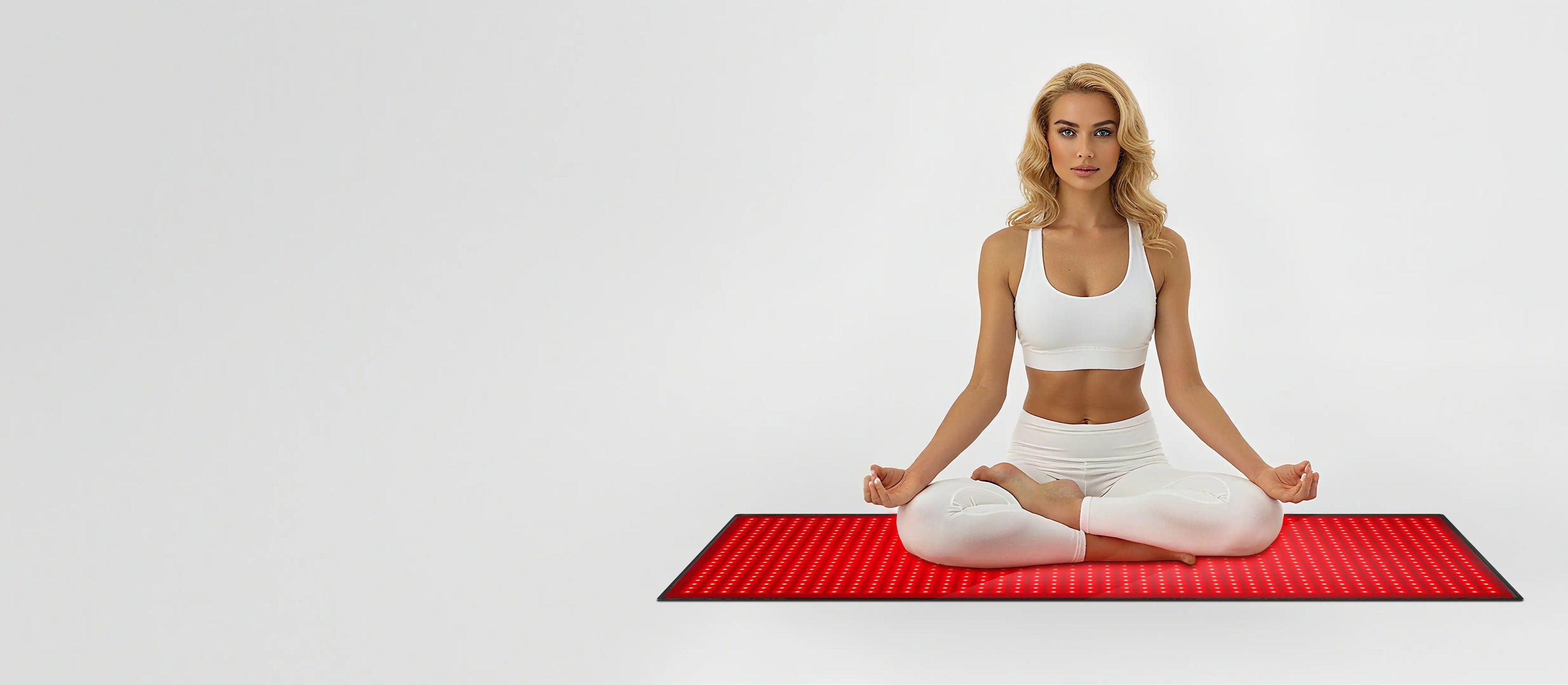 Woman in lotus pose using a red light therapy mat on a minimalist white background, right-aligned hero banner.
