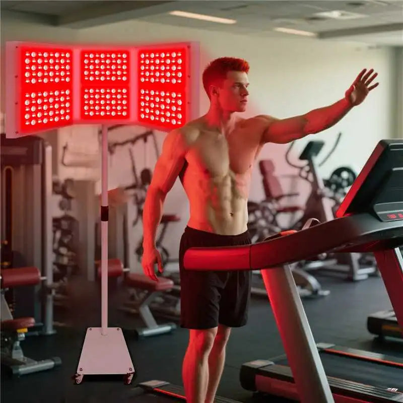 Athletic man warming up on a treadmill in a gym, illuminated by a Youlumi YL-IRP010-H06T foldable tri-panel red light therapy device on a mobile stand